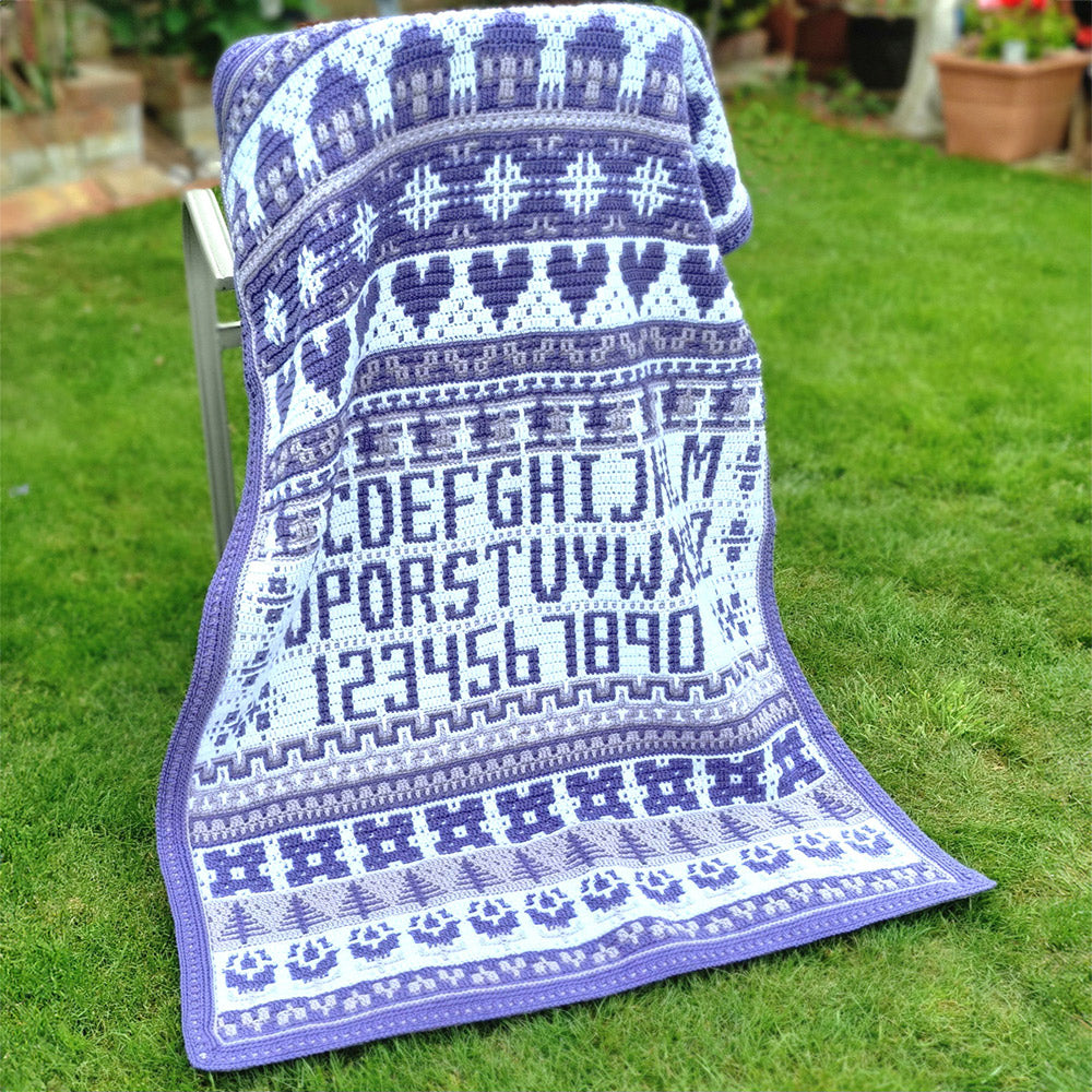 Rosina Plane Lakenham Mosaic Sampler CAL Haakpakket - Ultra Violet deken gedrapeerd in de tuin