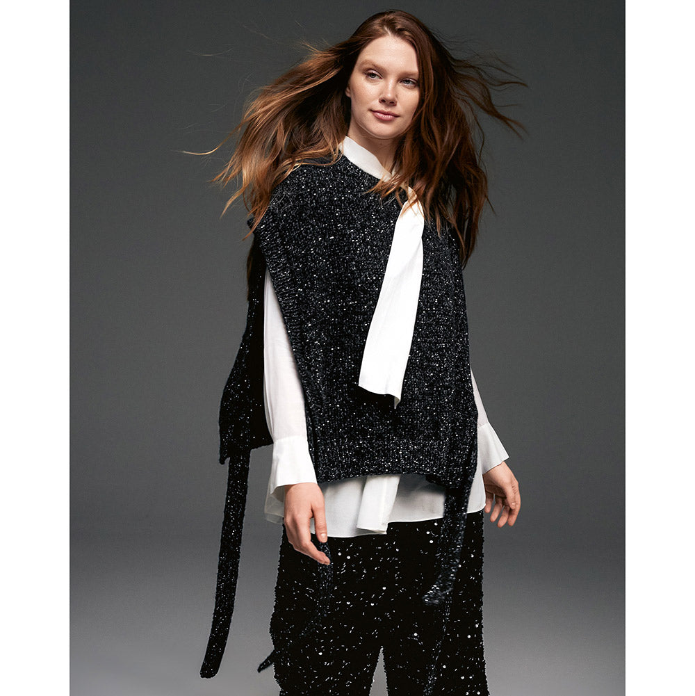Lana Grossa Glamour 018 Goudgeel sfeerfoto - model draagt een gebreide slipover met open zijkanten, bindceintuur en glanzende pailletten