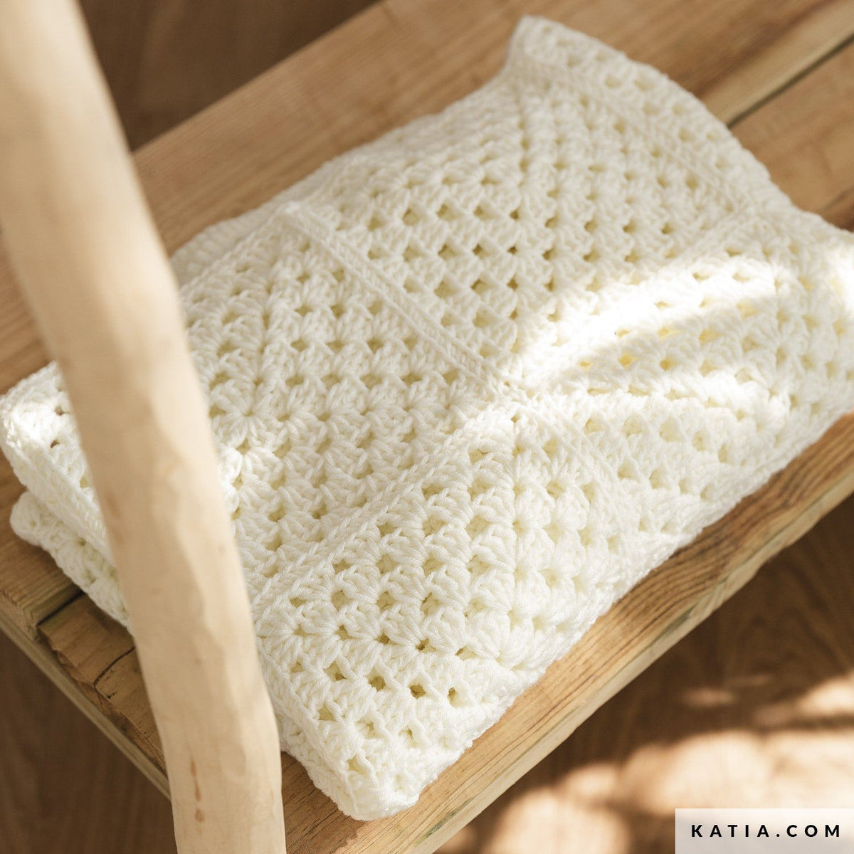 Ecru Katia The Basic granny square babydeken gedrapeerd in babykamer