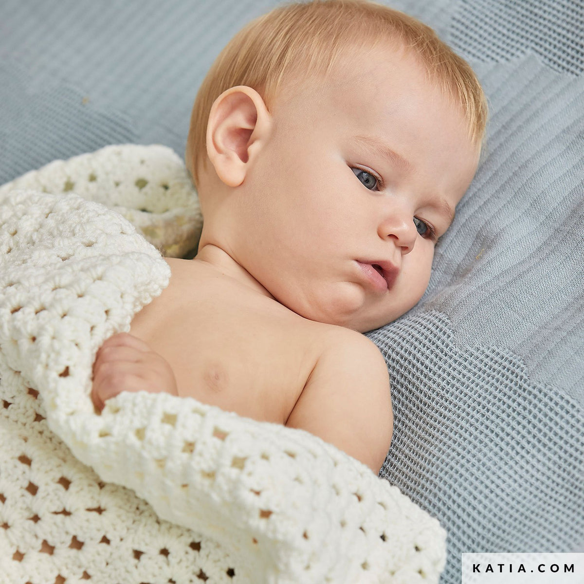 Baby onder een ecru Katia The Basic granny square deken